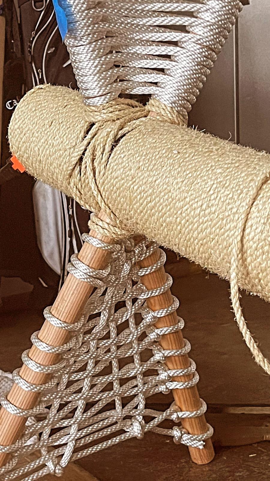 The woven rope hammock platform structure close up, with white rope strung between wooden dowels.
